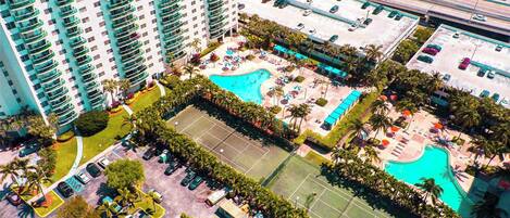 A high-rise hotel with a rooftop pool, tennis court, and multiple parking levels.