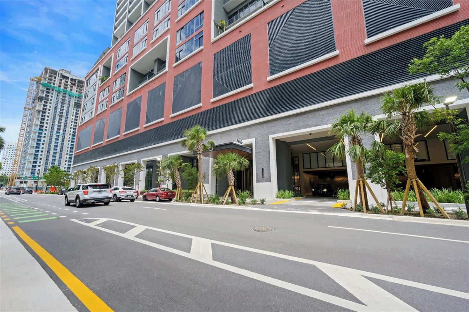A modern building with a red facade, multiple balconies, and a parking garage entrance.