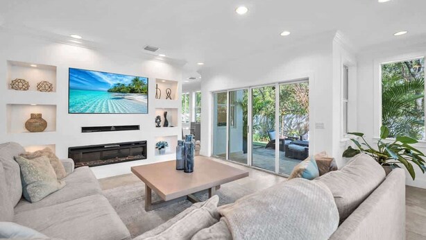 A modern living room with a large flat-screen TV, a fireplace, and a comfortable seating area.