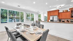 A modern kitchen with wooden cabinets, stainless steel appliances, and a dining area with a large table and chairs.