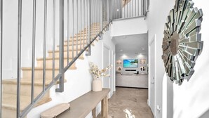 A modern interior with a staircase, a bench, and a decorative wall piece.