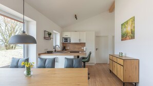 Une cuisine moderne avec des armoires blanches, un plan de travail en bois et un four à micro-ondes encastré.