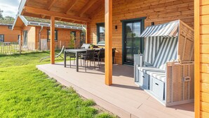 Une terrasse en bois avec des sièges extérieurs et un espace abrité.