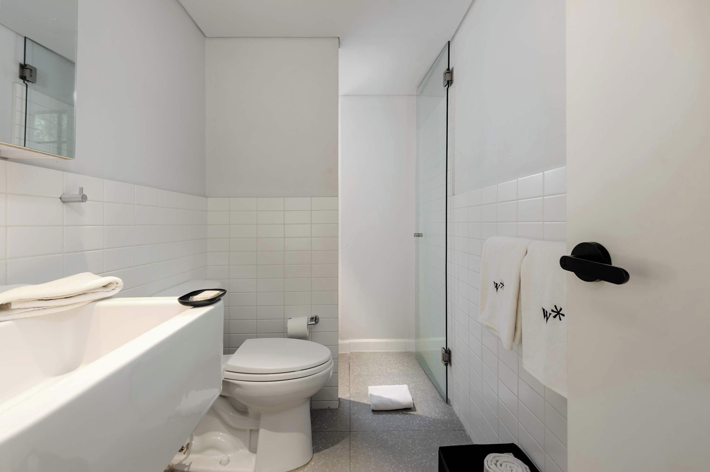 Un baño moderno con una bañera blanca, inodoro y cabina de ducha de vidrio.