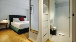 Hotellihuone, jossa on sänky, yöpöytä, peili sekä kylpyhuone, jossa on suihku ja wc.