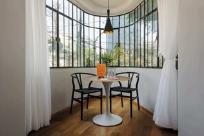 A room with a curved window, a round table with two chairs, a hanging light fixture, and a potted plant on the table. - w* | Intimate 2BR in Roma Norte (Ciudad de México)