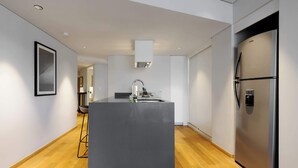 Ett modernt kök med en central köksö, vitvaror i rostfritt stål och en minimalistisk design.