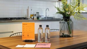 A reception desk with a welcome sign, two water bottles, and a vase with green plants. - w* | Radiant 2BR in Roma Norte (Ciudad de México)