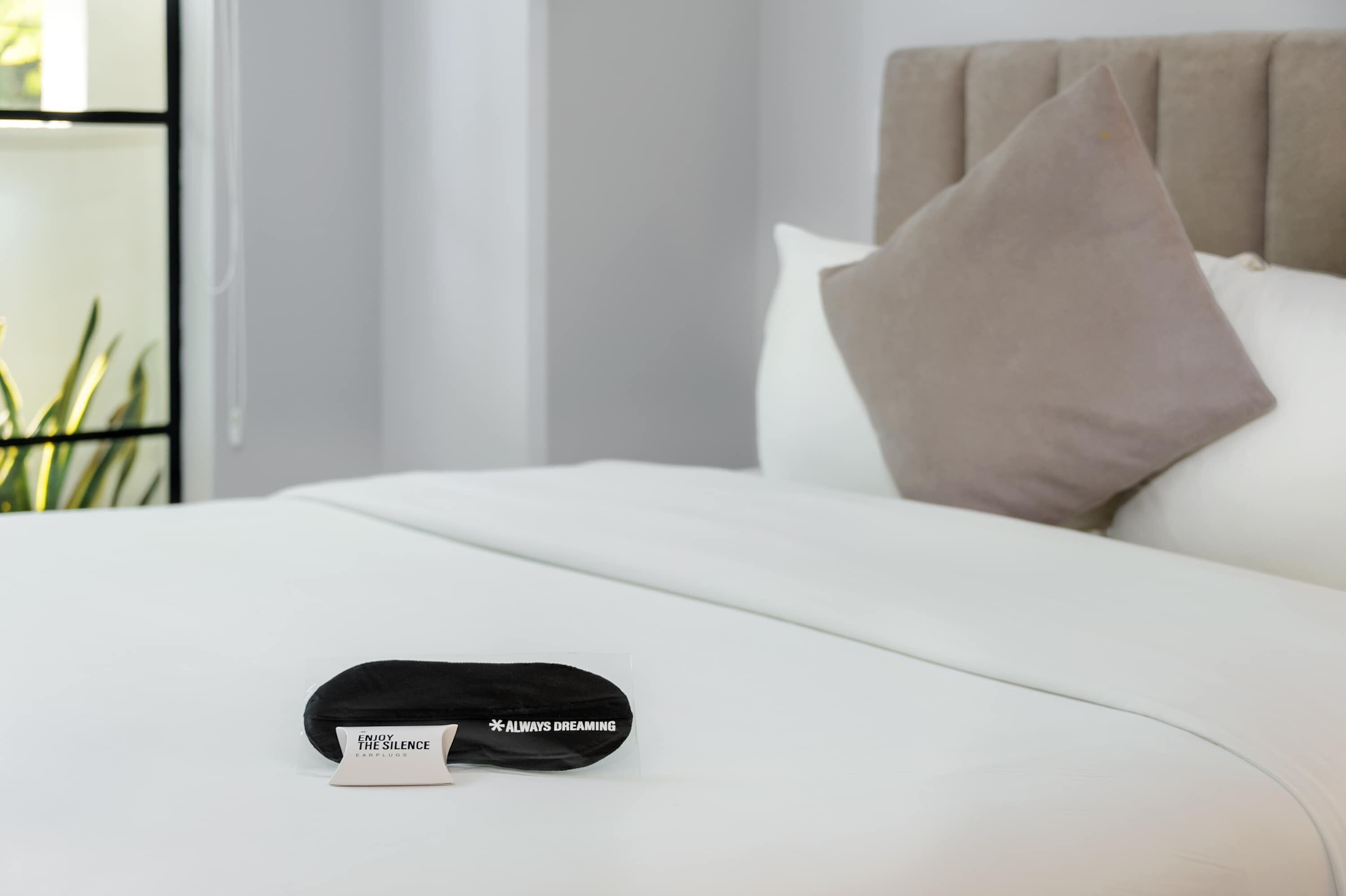 Una cama bien hecha con una almohada y un objeto negro encima.