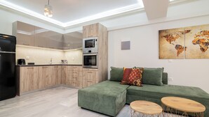 A modern kitchen with built-in appliances and a green sofa in the living area.