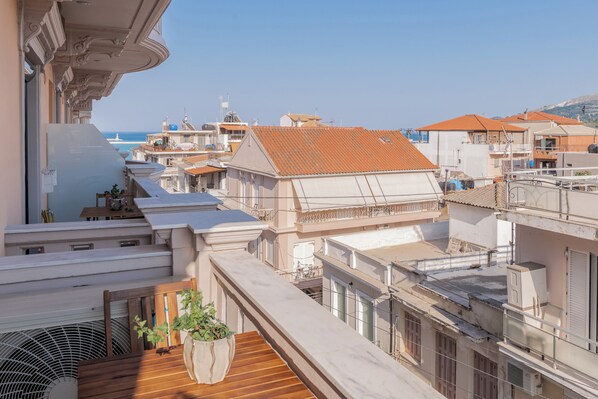 A high-rise building with multiple balconies, a view of the sea, and a rooftop terrace with a potted plant.