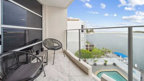 Un balcón con piscina, sillas y vistas al mar.