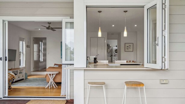 Una cocina moderna con una isla central, dos taburetes de bar e iluminación colgante.