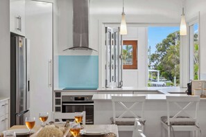 Una cocina moderna con armarios blancos, una campana extractora de acero inoxidable y vistas al exterior.