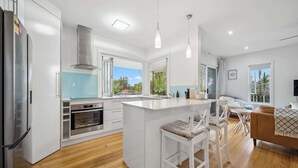 Una cocina moderna con armarios blancos, una isla central y un comedor con un sofá marrón.