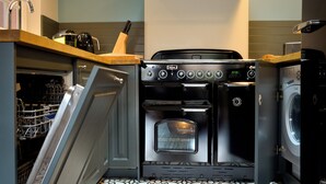 A compact kitchen with a built-in oven and dishwasher, a coffee maker, and a knife block on the countertop.