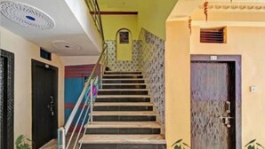 A staircase with a handrail, a door with a patterned design, and a wall with a decorative element. - DhamStay Hotel Shree Bhumi Near SeaBeach (Puri)