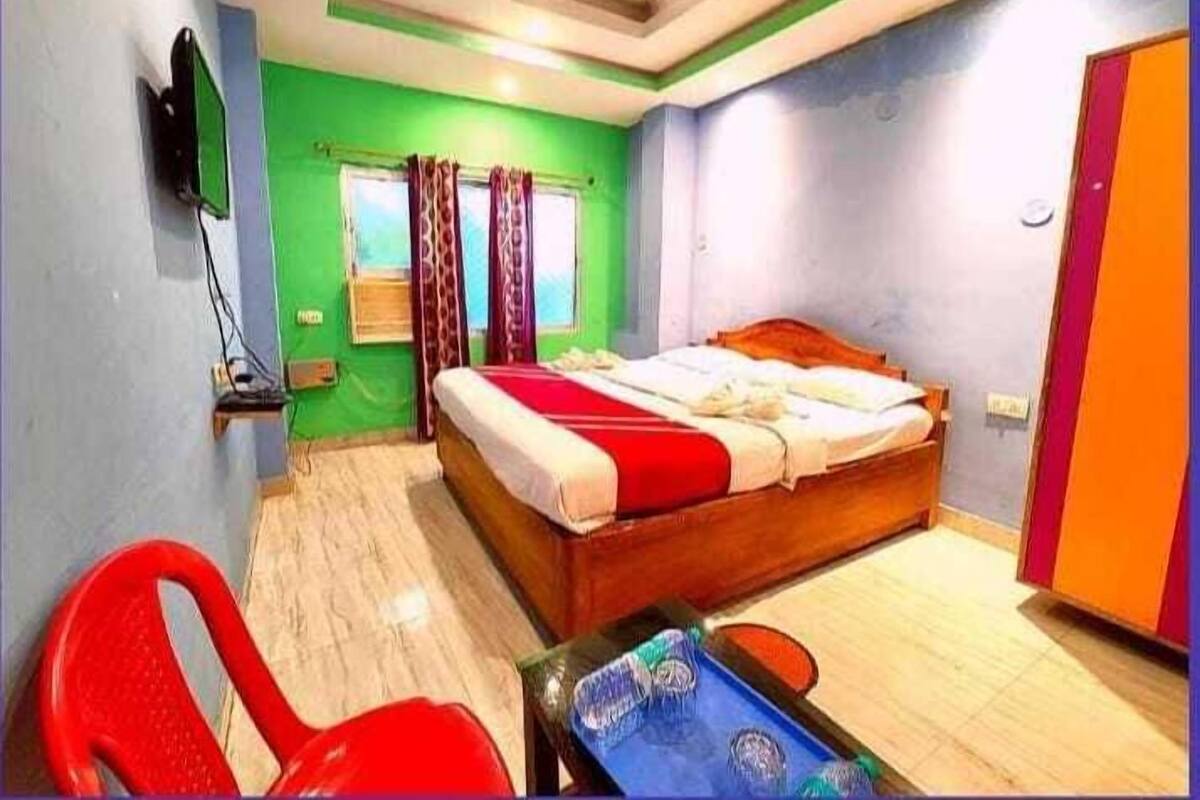 A bedroom with a bed, a desk, a chair, a television, and a window with curtains.