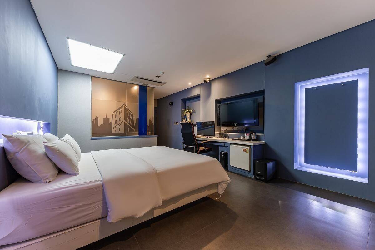 A modern hotel room with a bed, desk, and TV.