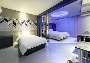 Quarto de hotel moderno com duas camas, uma escrivaninha e banheiro com chuveiro e vaso sanitário.