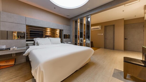 A modern hotel room with a large bed, a desk, and a built-in TV. - HOTEL ON (Uiwang)