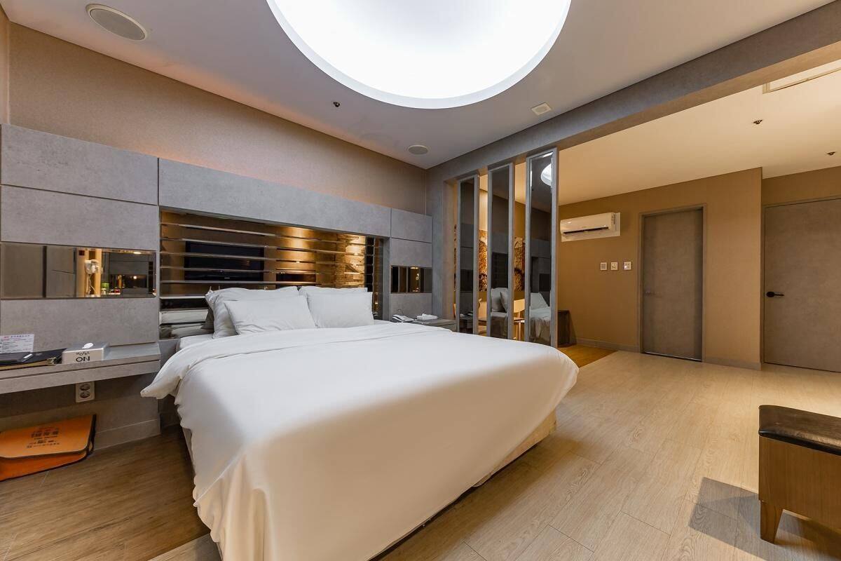 A modern hotel room with a large bed, a desk, and a built-in TV.