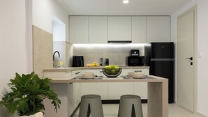 Una cocina moderna con una isla central, dos taburetes, una cafetera y un refrigerador.