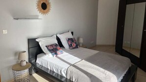 A bedroom with a bed, bedside lamps, a wall-mounted sun decoration, and a wardrobe. - Comfortable accommodation, SPA and Heated swimming-pool (Le Tampon)