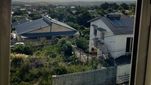A residential area with houses, some with solar panels, and a clear sky with the sun visible. - Comfortable accommodation, SPA and Heated swimming-pool (Le Tampon)