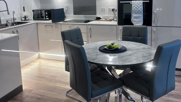A modern kitchen with grey cabinets, a stainless steel range hood, and a built-in oven.