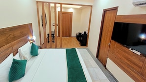Quarto de hotel com cama, televisão, escrivaninha e cadeira.