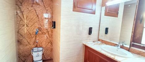 A bathroom with a marble wall, wooden vanity, and a large mirror.