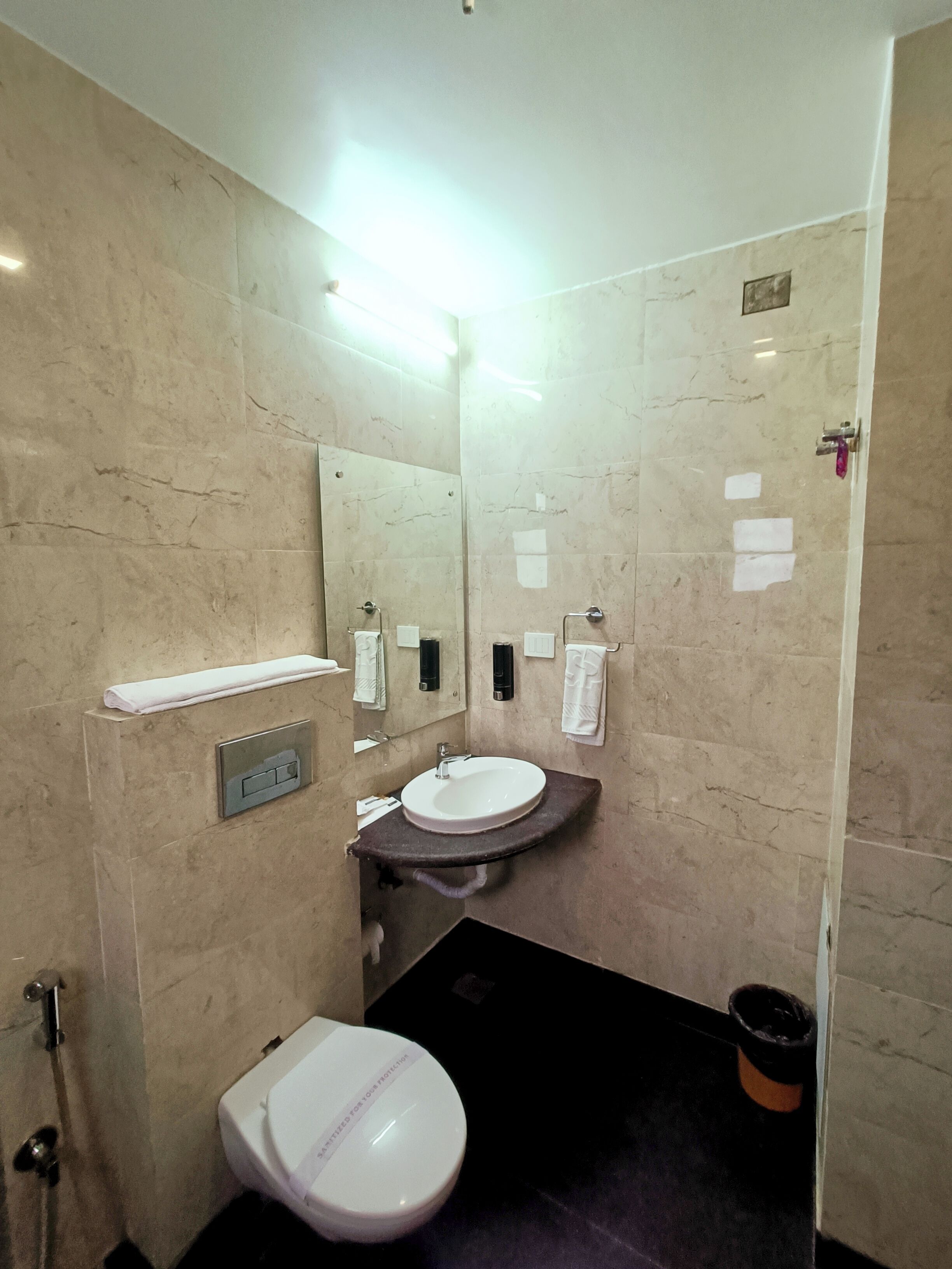 Un baño pequeño con inodoro, lavamanos y espejo blancos.