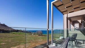 A balcony with a glass railing overlooking a coastal landscape. - Walking distance from the beach, villa complex with 2 pools! (Panormo)