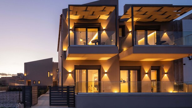 A modern multi-story building with balconies and large windows, featuring a flat roof design and a gated entrance. - Walking distance from the beach, villa complex with 2 pools! (Panormo)