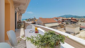 A balcony with a table set for breakfast, overlooking a cityscape with buildings and a mountain in the distance.