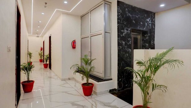 Un couloir doté d’un sol en marbre, de plantes en pot, d’un extincteur et d’un mur en marbre noir.