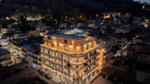A multi-story hotel with balconies, located in a densely built urban area with a mountainous backdrop. - ExAnimo Luxury Apt 6 (Zakinthos)