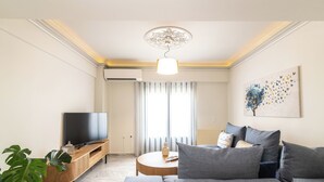 A modern living room with a flat-screen TV, grey sofa, wooden coffee table, and a potted plant. - ExAnimo Luxury Apt 6 (Zakinthos)