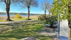 A grassy area with a paved path, a metal table, and a building with a brick wall. - Vacation apartment 3 "Hygge" Rügen, Baltic Sea, Seedorf am Neuensiener See (Sellin OT Seedorf)