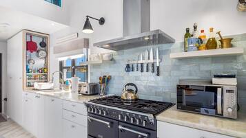 Una cocina moderna con horno empotrado, microondas y hervidor sobre la estufa.