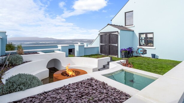 A modern house with a pool, a fire pit, and a view of the ocean. - Ocean Mist Luxurious Seaside Haven (Carna)