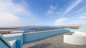 A terrace with a view of the sea, a white outdoor seating area, and a light blue wall. - Ocean Mist Cottage (Carna)