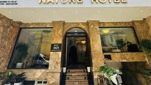 The Nature Hotel entrance with a grand archway, a sign indicating room rates, and a welcoming mat. - Nature Hotel - Le Dai Hanh (Xuan Huong - Da Lat)