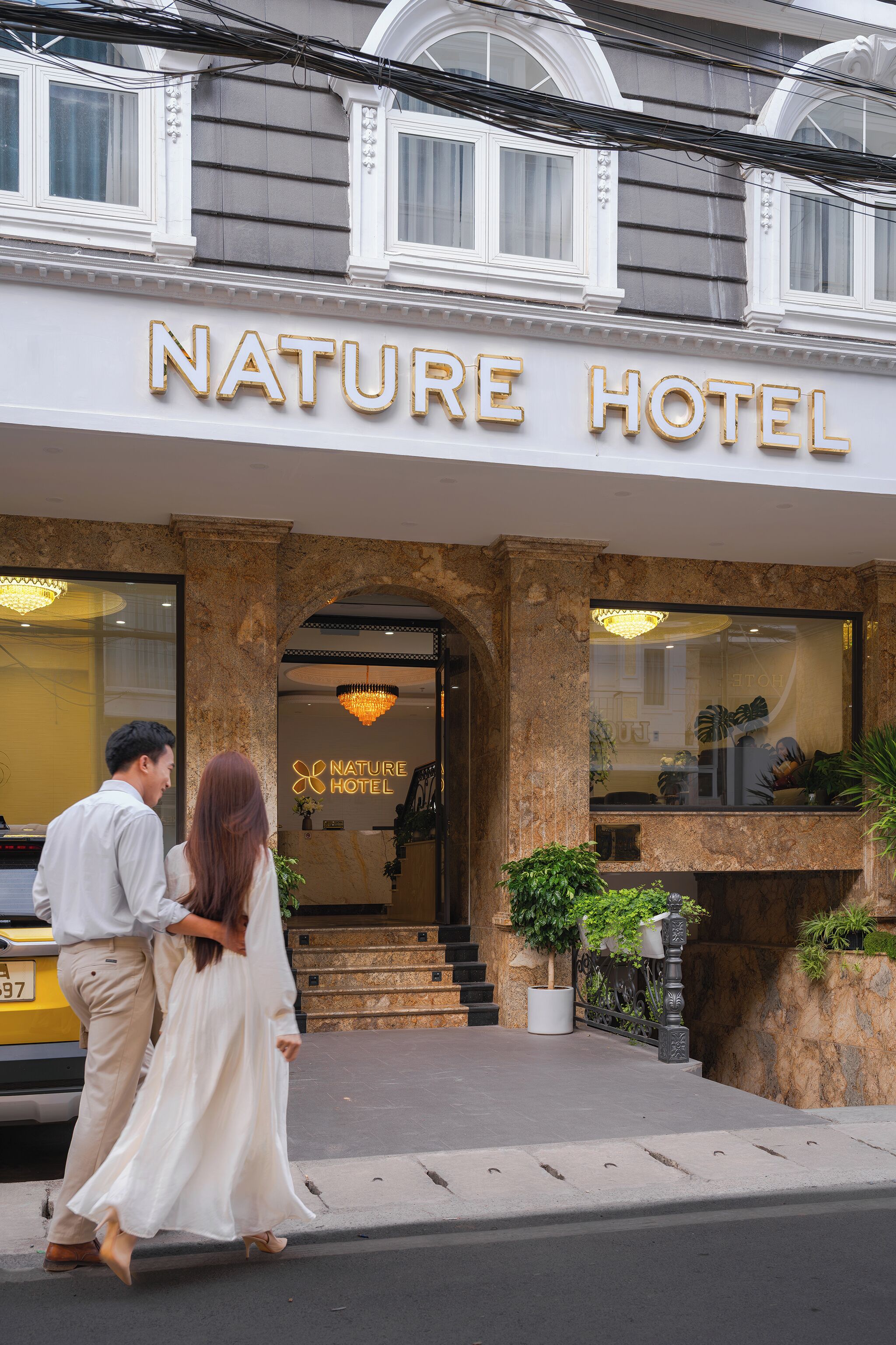 El exterior del Hotel Nature, con una entrada imponente, una araña y un letrero sobre la puerta.