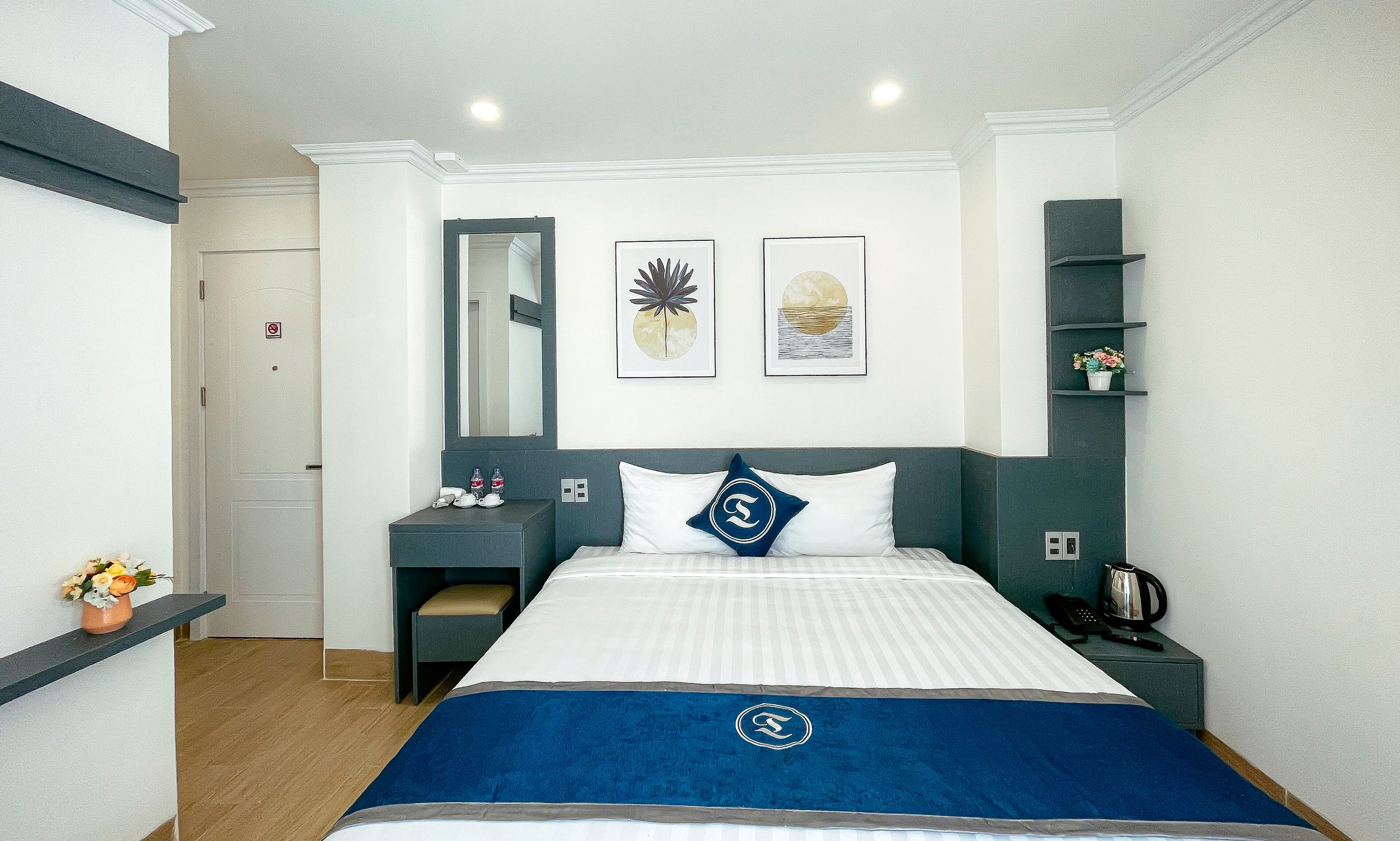 A hotel room with a bed, bedside table, nightstand, and a mirror.