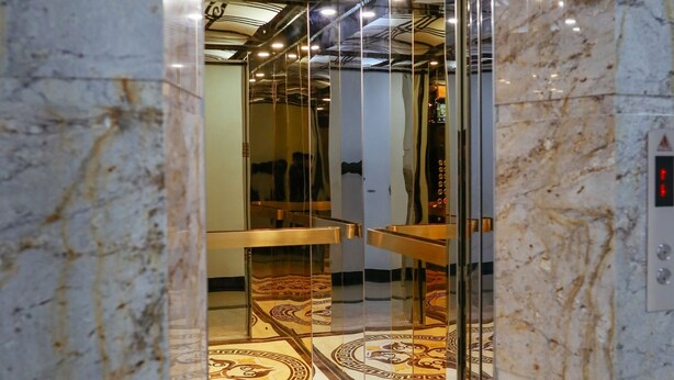 An elevator interior with marble walls and a patterned floor. - Nature Hotel - Le Dai Hanh (Xuan Huong - Da Lat)