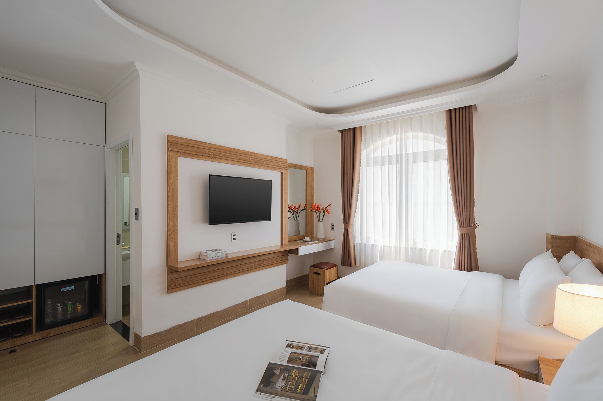 Una camera d'albergo con un letto, una televisione, una scrivania e un frigobar.