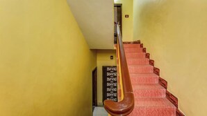 A staircase with a wooden handrail and red steps, leading to a door with a patterned design. - DhamStay Hotel Moon Near Niladri Beach (Puri)