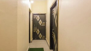 A narrow hallway with a green carpet leading to a door with a geometric pattern. - DhamStay Hotel Moon Near Niladri Beach (Puri)